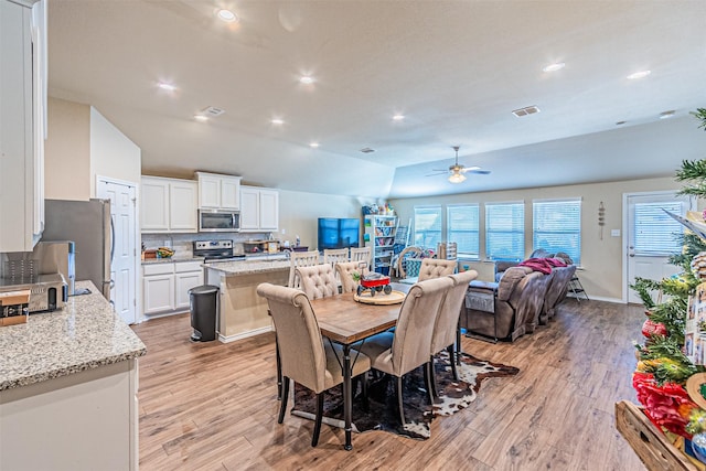 dining space featuring vaulted ceiling, light hardwood / wood-style floors, and a healthy amount of sunlight