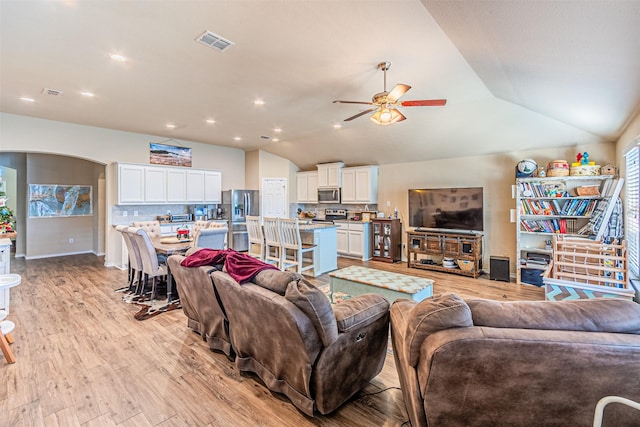 living room featuring vaulted ceiling, ceiling fan, and light wood-type flooring