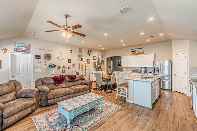 living room featuring ceiling fan, lofted ceiling, sink, and light hardwood / wood-style flooring