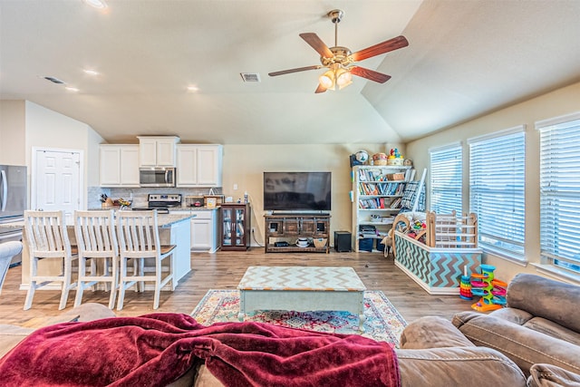 living room featuring ceiling fan, lofted ceiling, and light hardwood / wood-style floors