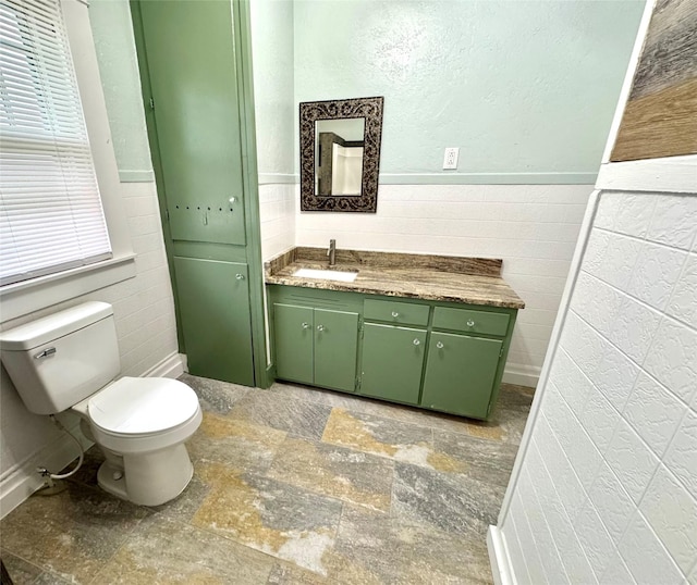 bathroom featuring vanity, tile walls, and toilet