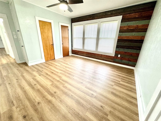 unfurnished bedroom featuring multiple closets, ceiling fan, and light wood-type flooring