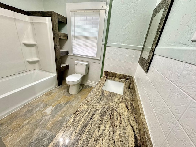 full bathroom with tile walls, vanity, shower / bathtub combination, and toilet