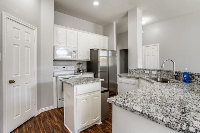 kitchen featuring white appliances, sink, kitchen peninsula, light stone countertops, and white cabinetry