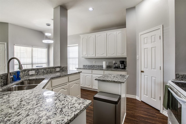 kitchen featuring electric stove, sink, white cabinetry, a center island, and light stone countertops