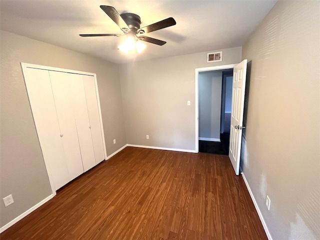 unfurnished bedroom with dark hardwood / wood-style flooring, a closet, and ceiling fan