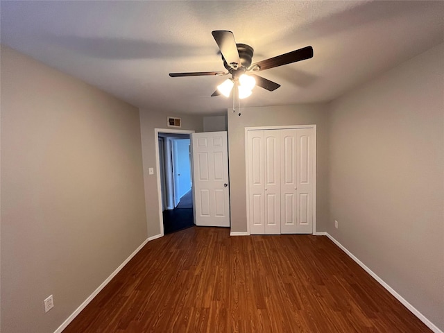 unfurnished bedroom with a closet, ceiling fan, and dark wood-type flooring