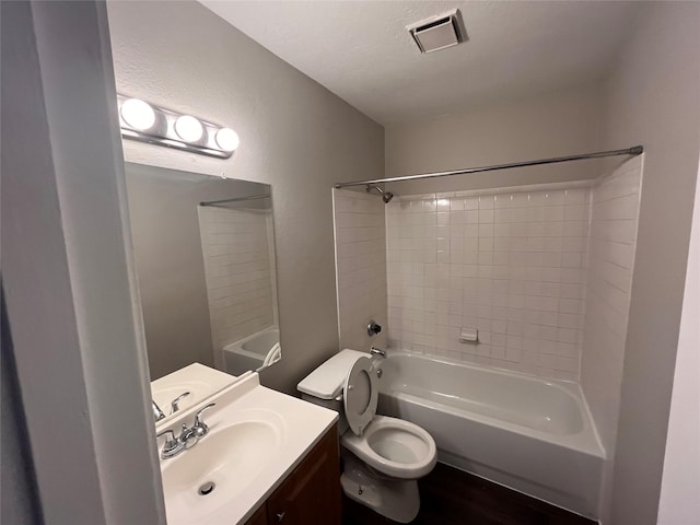 full bathroom with a textured ceiling, vanity, hardwood / wood-style floors, toilet, and tiled shower / bath