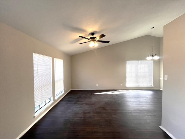 spare room featuring vaulted ceiling, dark hardwood / wood-style floors, and ceiling fan with notable chandelier