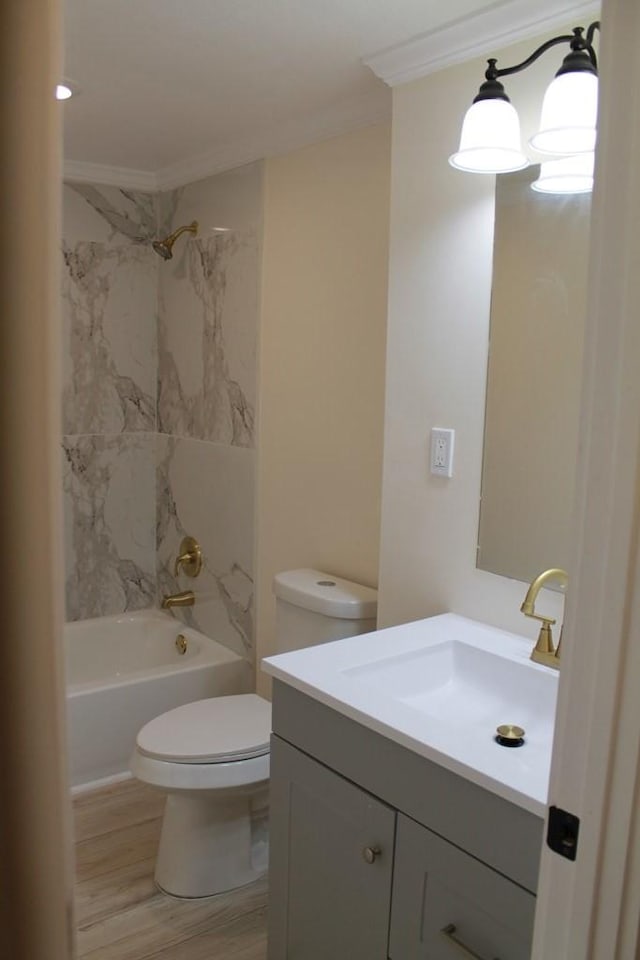 full bathroom with vanity, wood-type flooring, ornamental molding, tiled shower / bath, and toilet