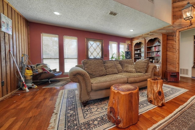 living room featuring hardwood / wood-style floors, a textured ceiling, and wood walls