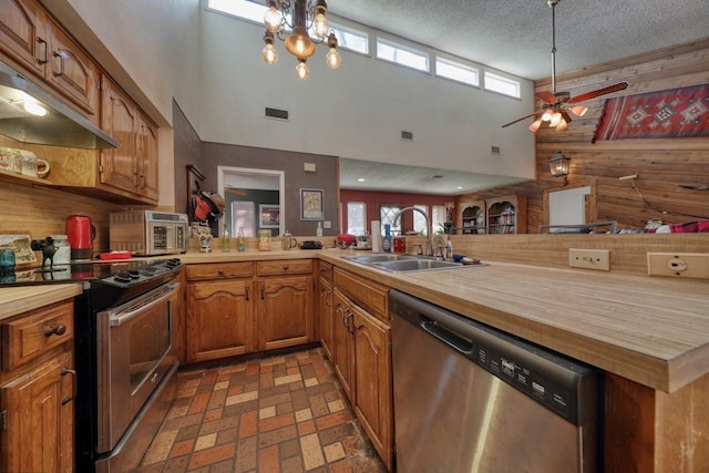 kitchen featuring a high ceiling, sink, butcher block countertops, kitchen peninsula, and stainless steel appliances