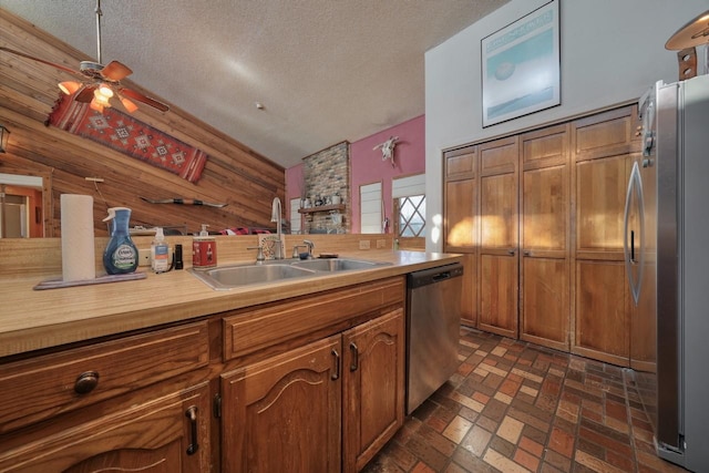 kitchen with wood walls, sink, stainless steel appliances, and a textured ceiling