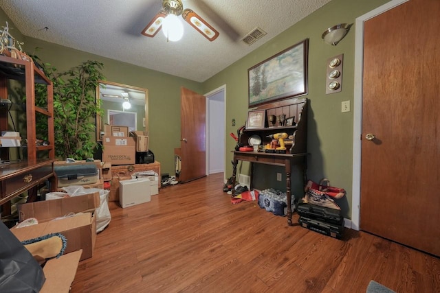 miscellaneous room with hardwood / wood-style floors, ceiling fan, and a textured ceiling