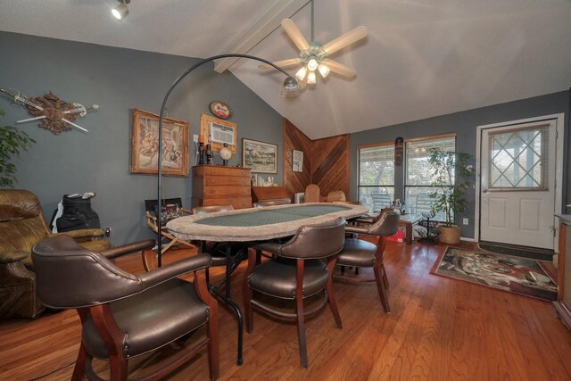 dining space with ceiling fan, lofted ceiling with beams, wooden walls, and light hardwood / wood-style flooring