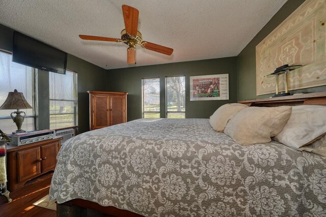 bedroom with ceiling fan, dark hardwood / wood-style flooring, and a textured ceiling