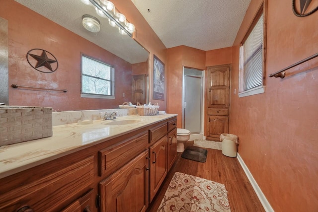 bathroom featuring vanity, a textured ceiling, a shower with door, hardwood / wood-style floors, and toilet