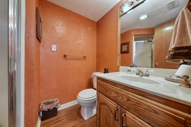 bathroom with vanity, toilet, a textured ceiling, an enclosed shower, and wood-type flooring