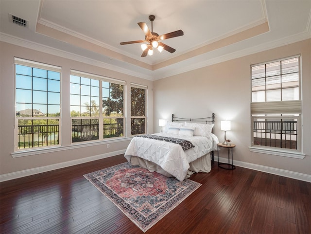 bedroom with a tray ceiling, ceiling fan, crown molding, and dark hardwood / wood-style floors