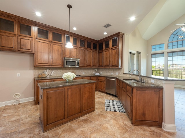 kitchen with kitchen peninsula, appliances with stainless steel finishes, sink, a center island, and hanging light fixtures