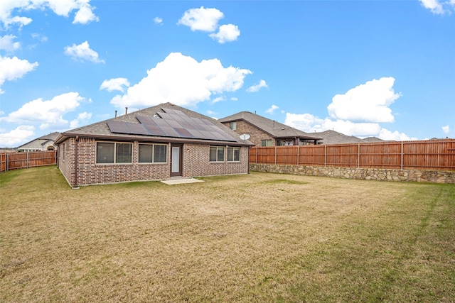 back of house with a lawn and solar panels