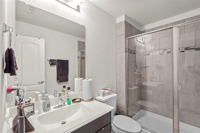 bathroom featuring a shower with door, vanity, and toilet