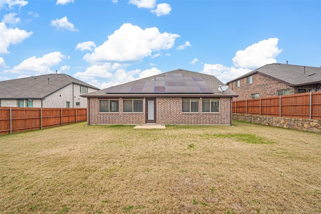 back of property featuring solar panels and a yard