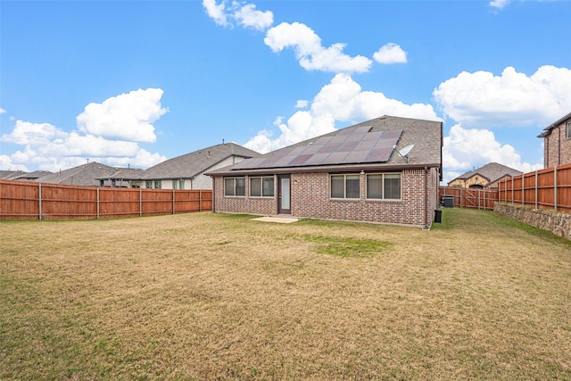 rear view of property featuring solar panels and a yard