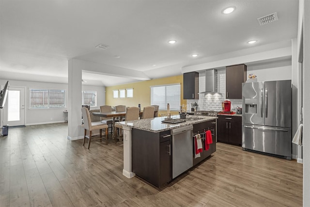 kitchen with wall chimney exhaust hood, a center island, dark brown cabinetry, and stainless steel appliances