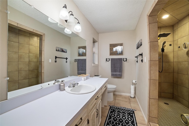 bathroom with tile patterned flooring, vanity, tiled shower, toilet, and a textured ceiling