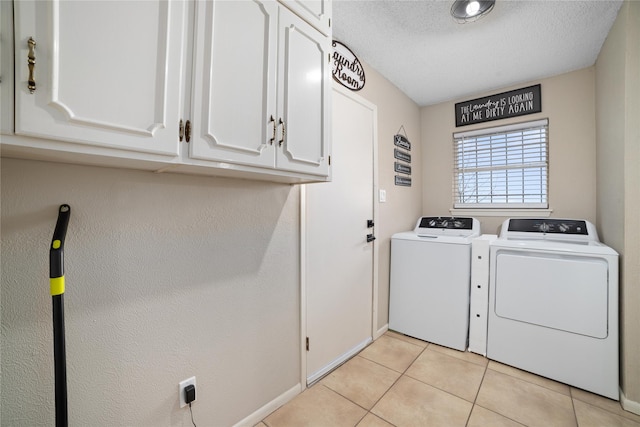 laundry area with cabinets, light tile patterned floors, a textured ceiling, and washing machine and clothes dryer