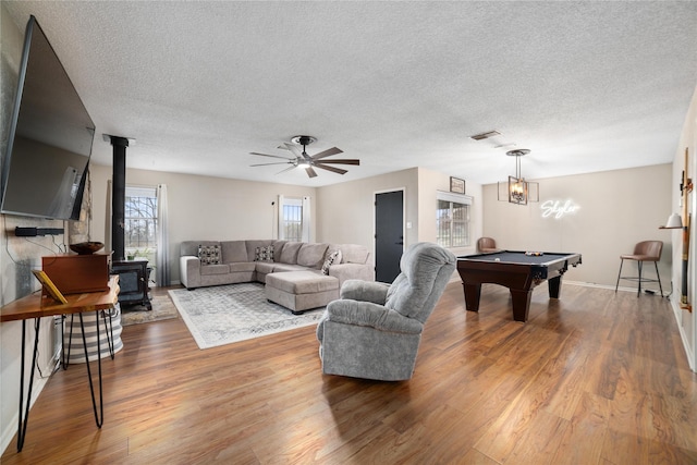 living room with hardwood / wood-style floors, pool table, a textured ceiling, and a wood stove