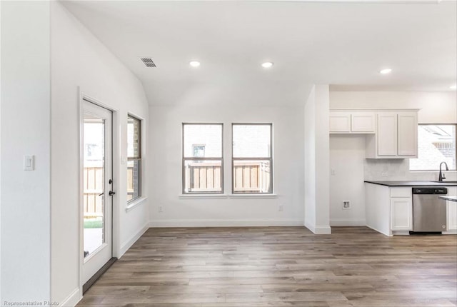 kitchen featuring white cabinetry, stainless steel dishwasher, light hardwood / wood-style floors, and sink