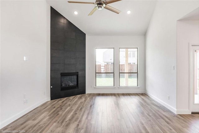 unfurnished living room featuring vaulted ceiling, ceiling fan, a fireplace, and light hardwood / wood-style flooring