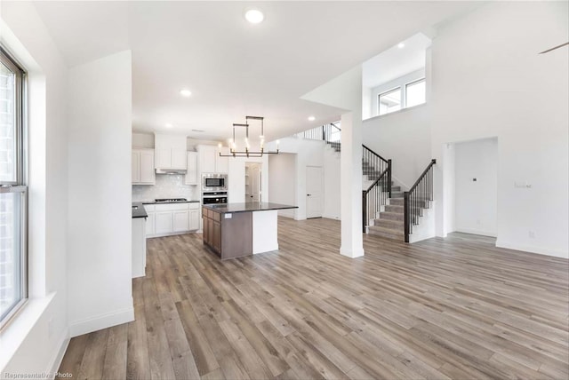 kitchen with a center island, backsplash, decorative light fixtures, white cabinets, and appliances with stainless steel finishes