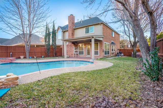 back of property featuring a yard, ceiling fan, and a swimming pool with hot tub