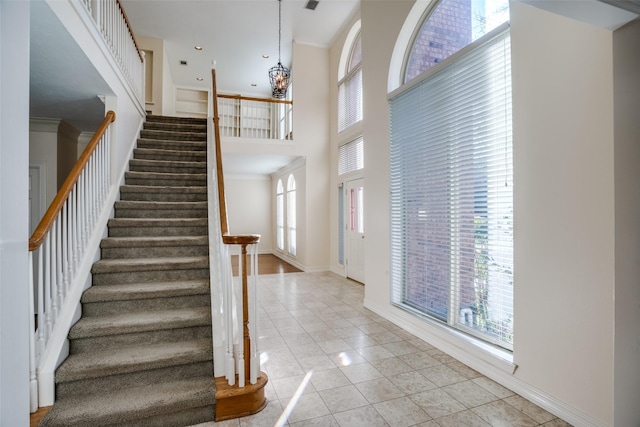 entryway with light tile patterned floors, an inviting chandelier, and a high ceiling