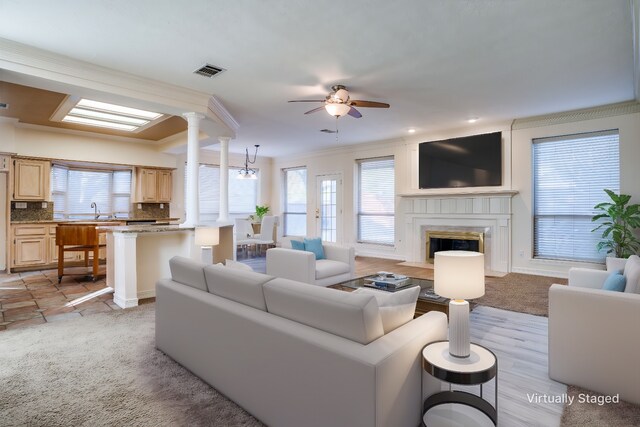 unfurnished living room featuring light carpet, crown molding, a premium fireplace, and ceiling fan with notable chandelier