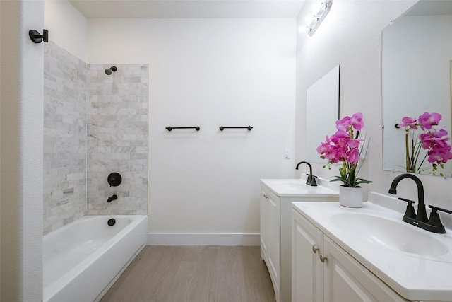 bathroom with hardwood / wood-style flooring, vanity, and tiled shower / bath combo