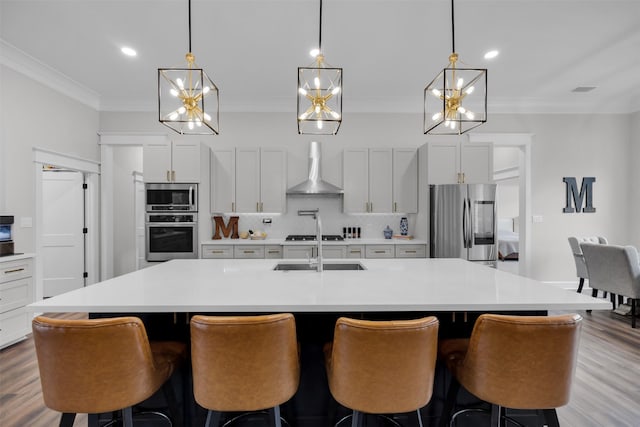 kitchen featuring a large island, stainless steel appliances, wall chimney range hood, decorative backsplash, and white cabinets