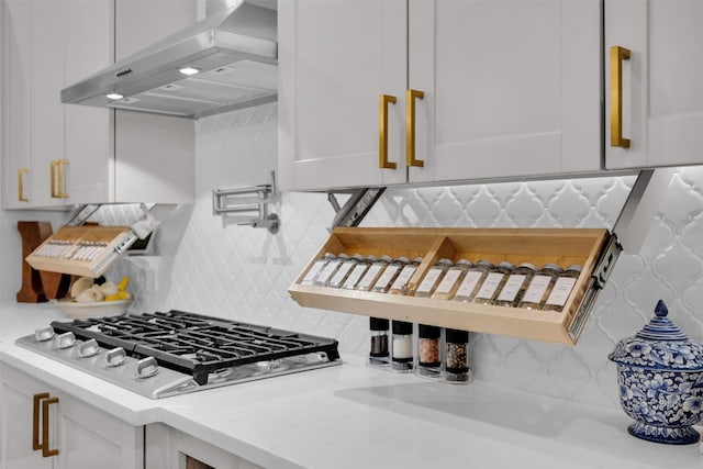 kitchen featuring white gas cooktop, white cabinetry, exhaust hood, and tasteful backsplash