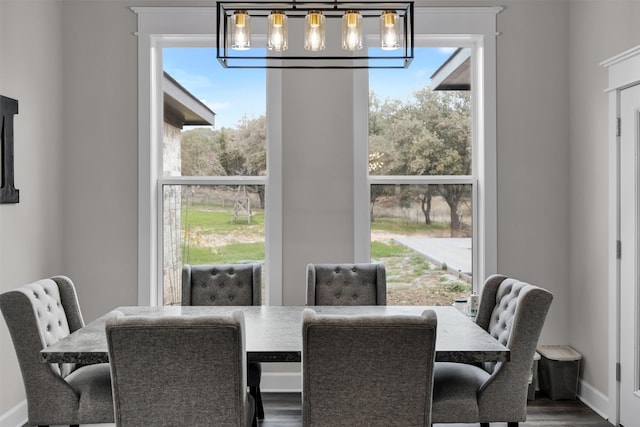 dining space with hardwood / wood-style flooring, plenty of natural light, and an inviting chandelier