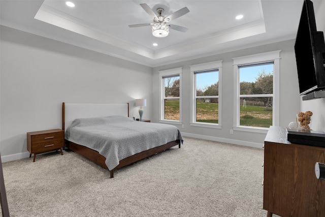 carpeted bedroom featuring a tray ceiling, multiple windows, and ceiling fan