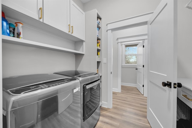 laundry room with cabinets, light hardwood / wood-style floors, and washing machine and clothes dryer