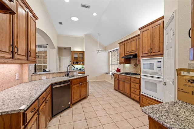 kitchen featuring a kitchen bar, kitchen peninsula, light stone counters, and stainless steel gas stovetop