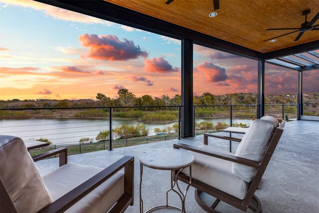 patio terrace at dusk with a water view and ceiling fan