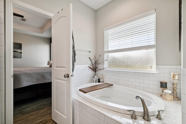 bathroom with tiled tub and hardwood / wood-style flooring