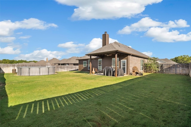 rear view of property featuring a yard and a fenced in pool