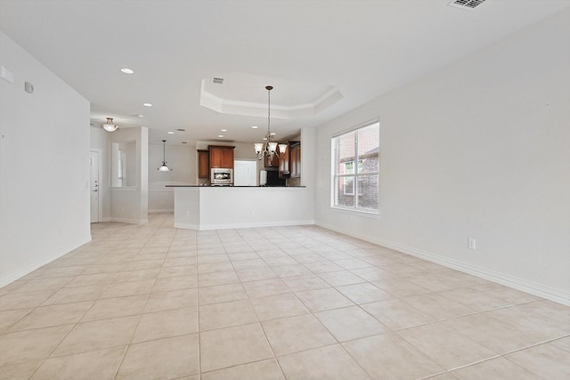 unfurnished living room with light tile patterned flooring, a raised ceiling, and an inviting chandelier