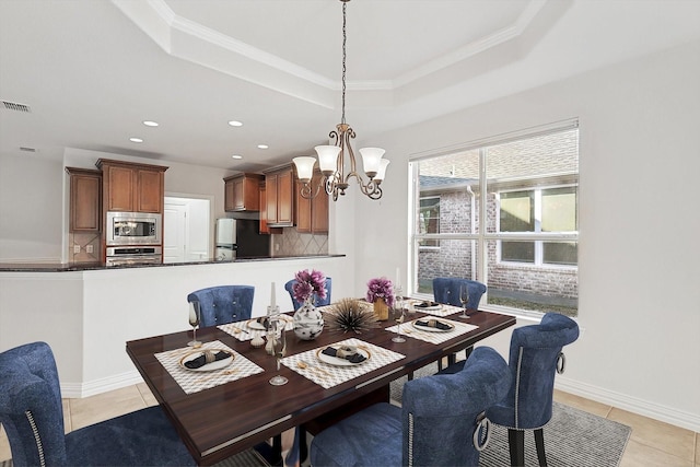 tiled dining area featuring a notable chandelier, crown molding, and a tray ceiling